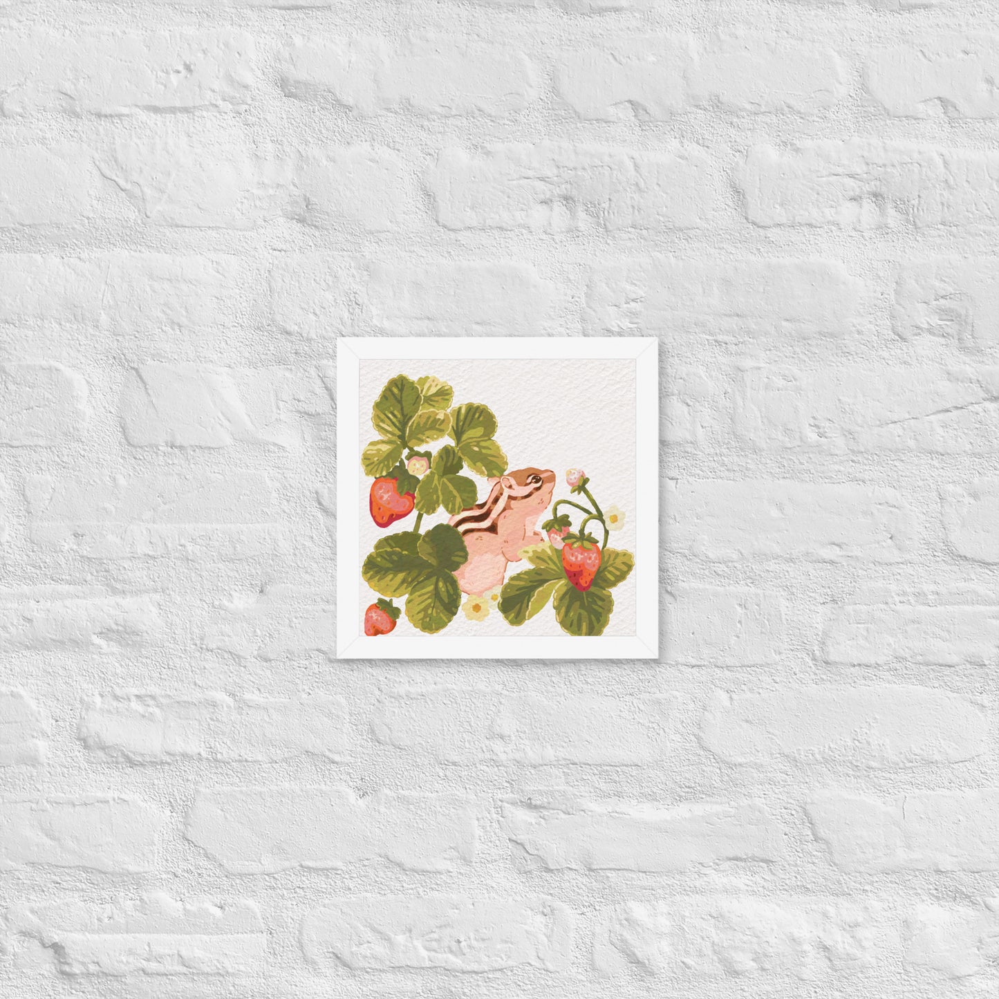 Framed artwork of a chipmunk among strawberry plants on a textured white wall.