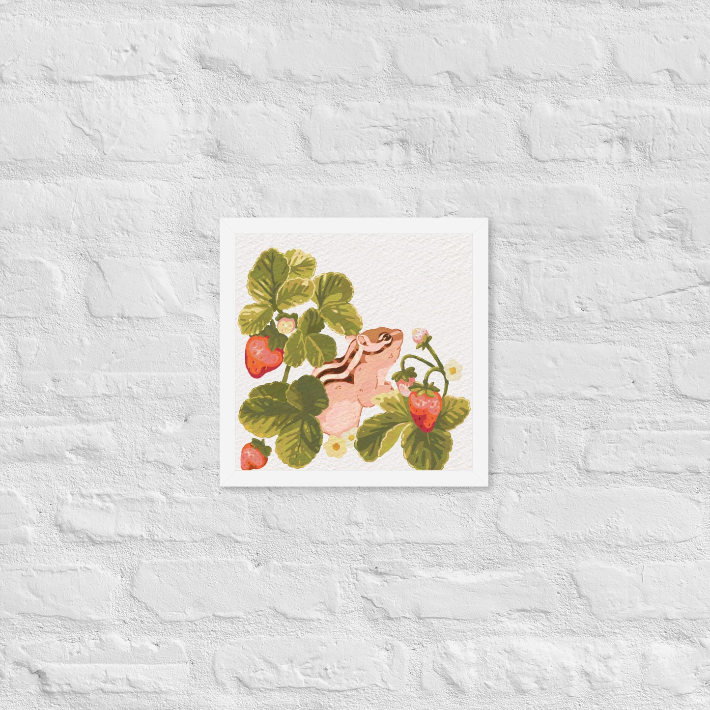 Framed artwork of a chipmunk among strawberry plants on a textured white wall.