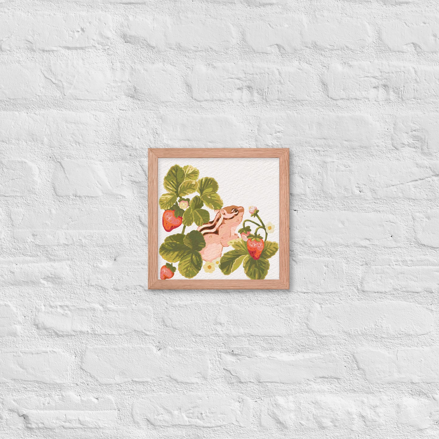 Framed artwork of a chipmunk among strawberry plants on a textured white wall.