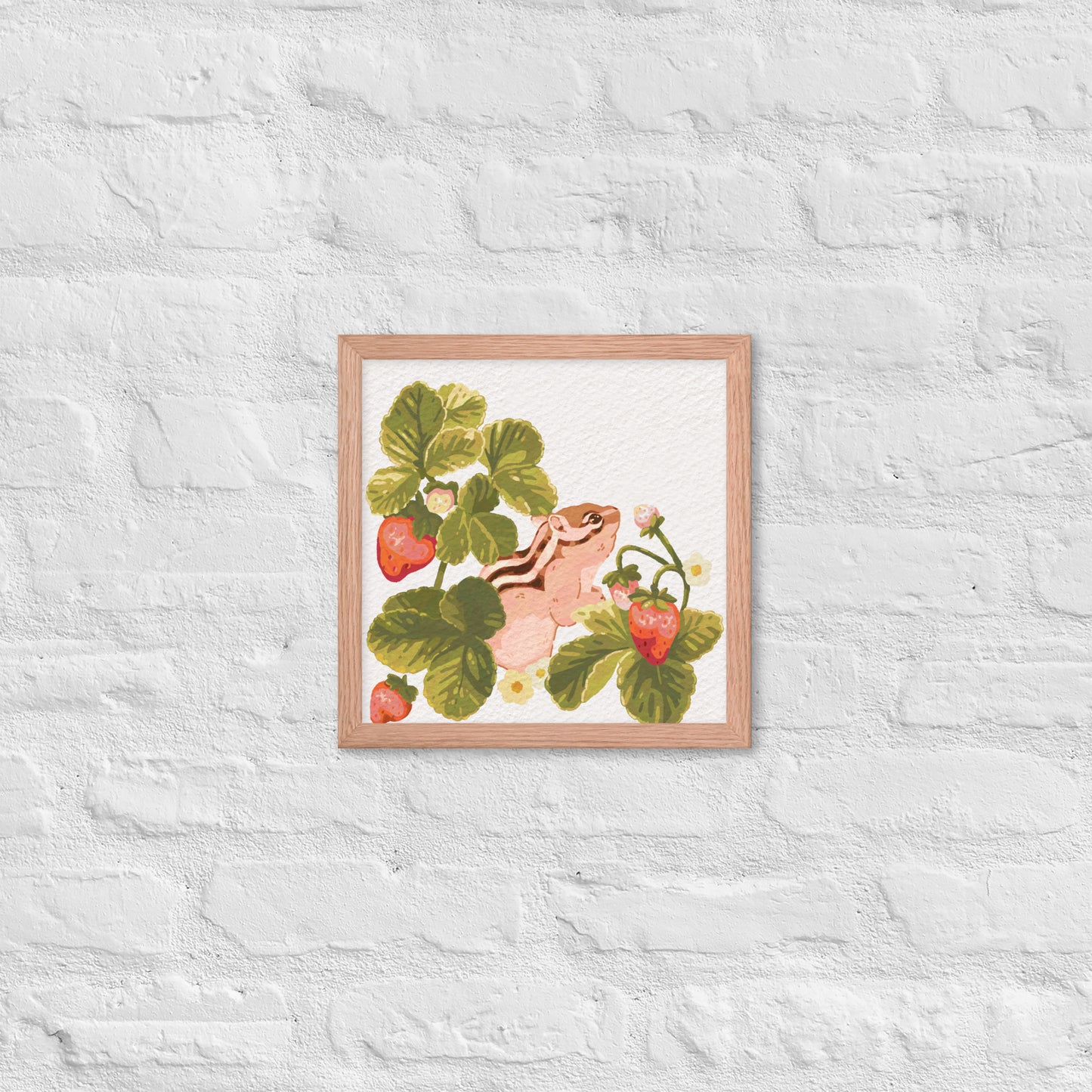 Framed artwork of a chipmunk among strawberry plants on a textured white wall.