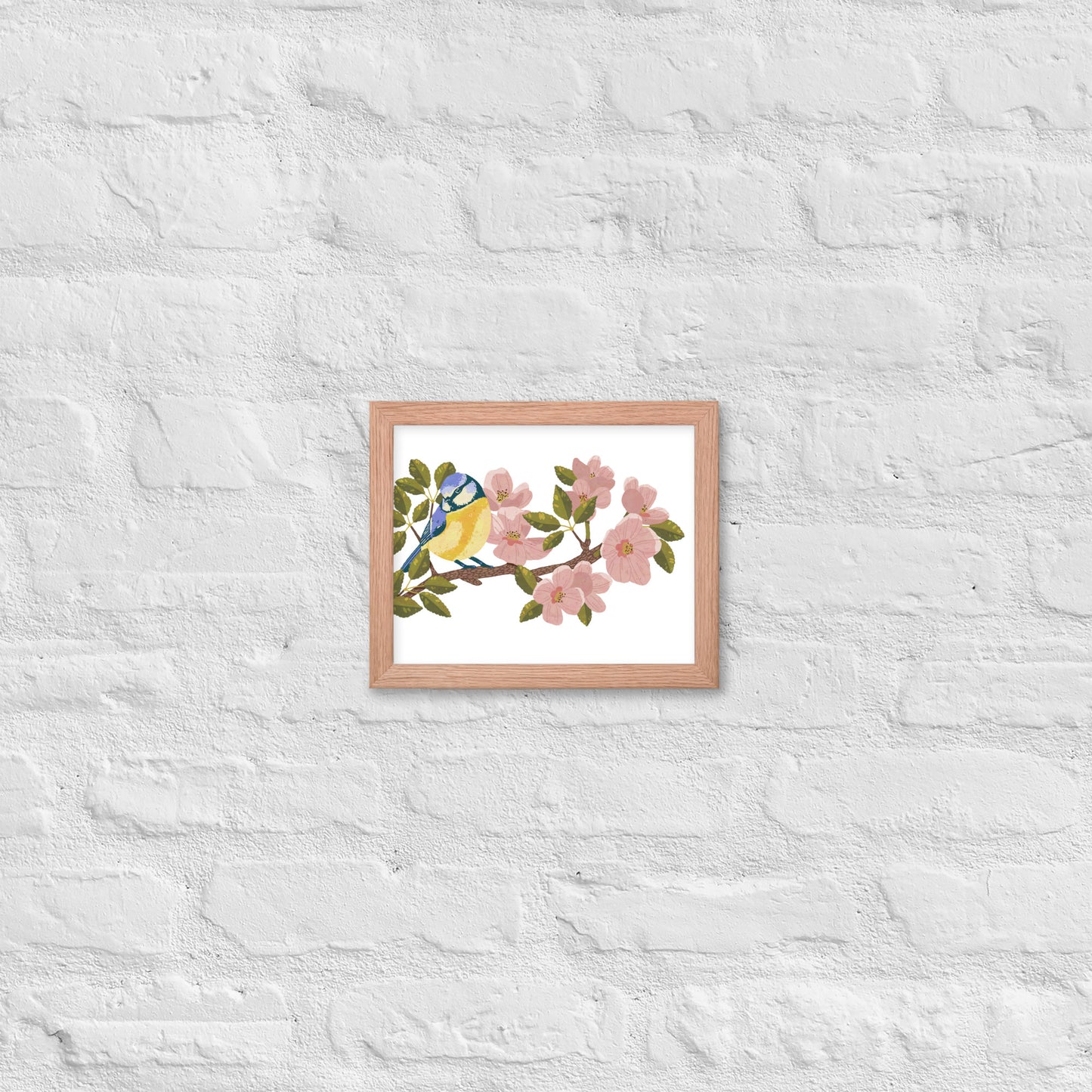 Framed artwork of a blue bird on a branch with pink flowers on a white textured wall.
