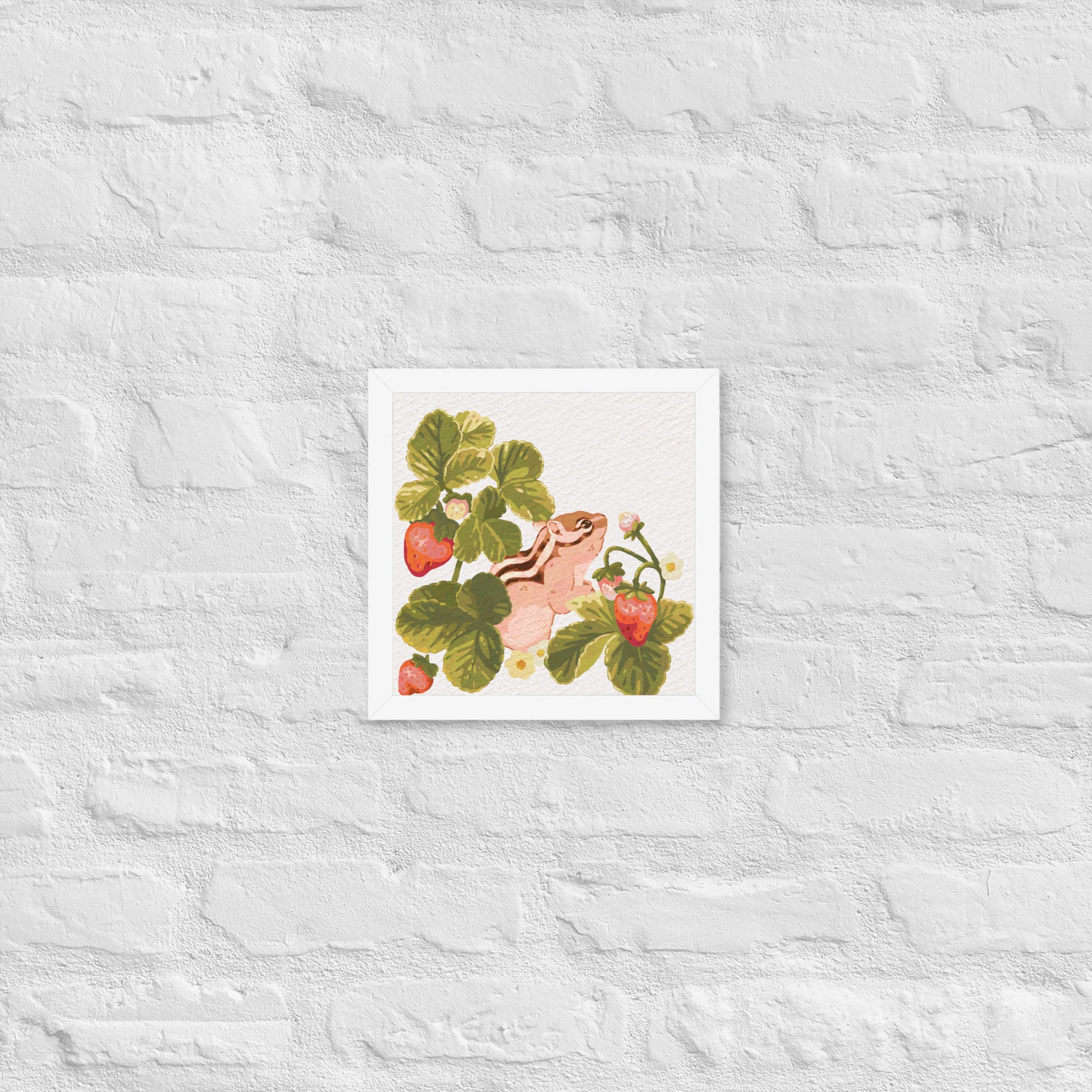 Framed artwork of a chipmunk among strawberry plants on a textured white wall.