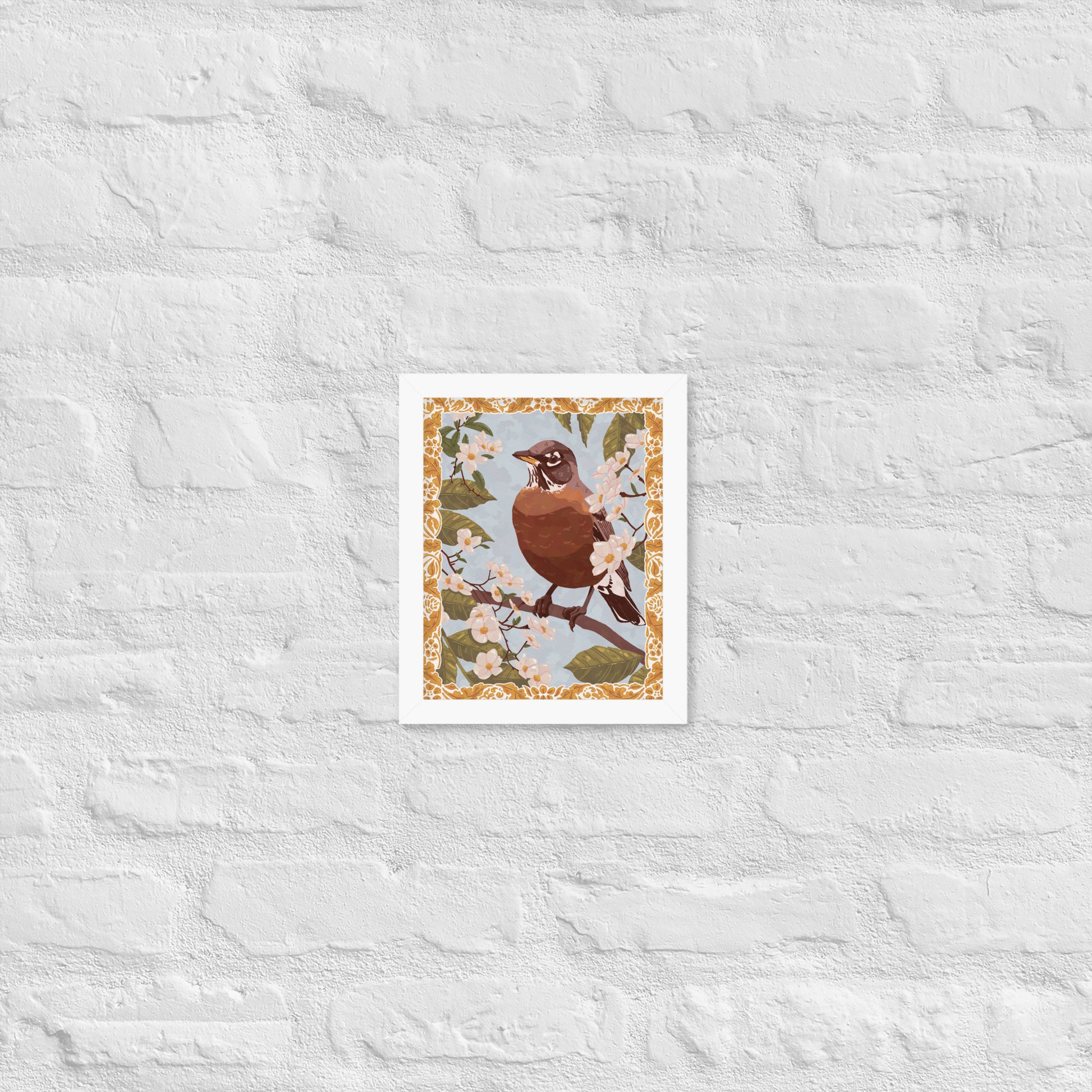 Framed artwork of a bird on a branch with flowers against a textured white wall.