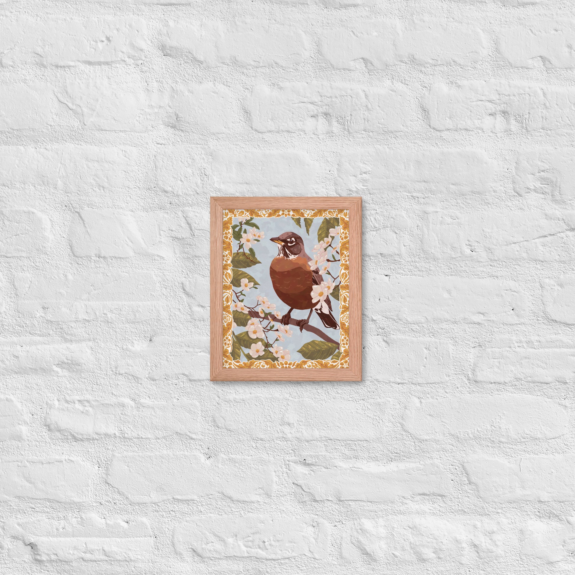 Framed artwork of a bird on a branch with floral patterns against a white textured wall.