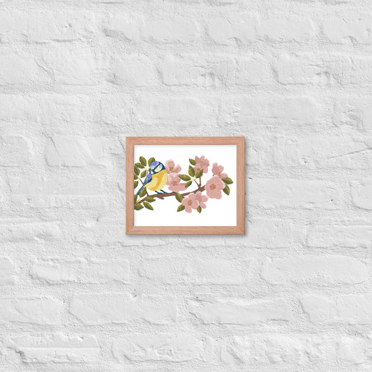 Framed artwork of a blue bird on a branch with pink flowers on a white textured wall.